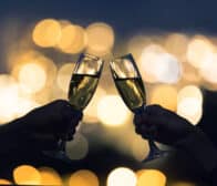 Couple toasting glasses of champagne agains a city night lights.